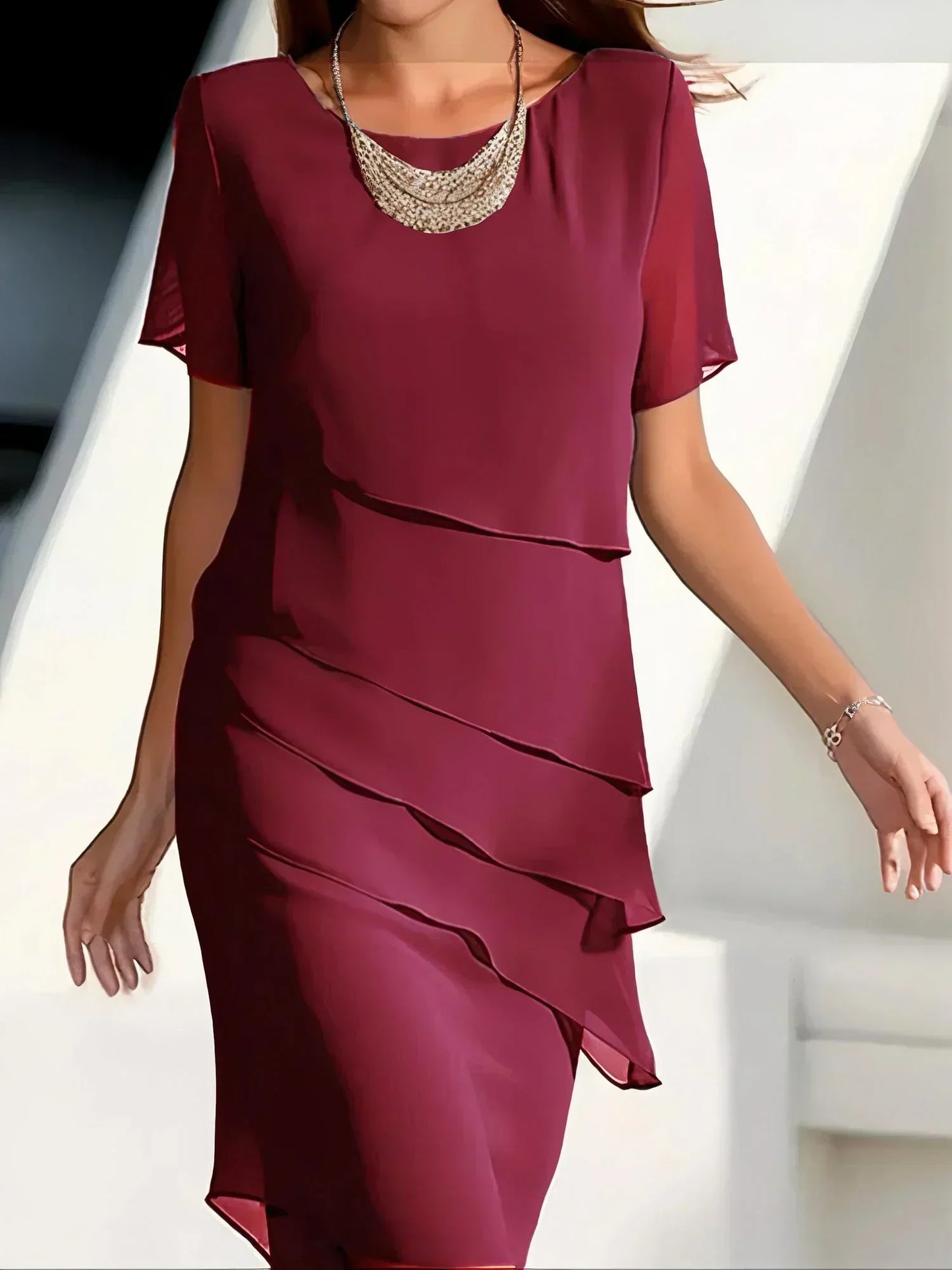 Maroon dress with ruffled layers worn by a person, against a neutral background