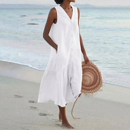 Woman in a white dress holding a straw hat on a beach