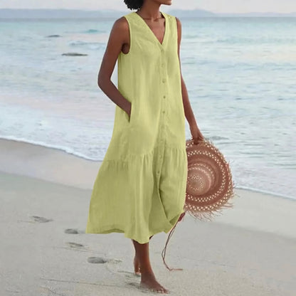 Woman in a yellow dress holding a straw hat on a beach