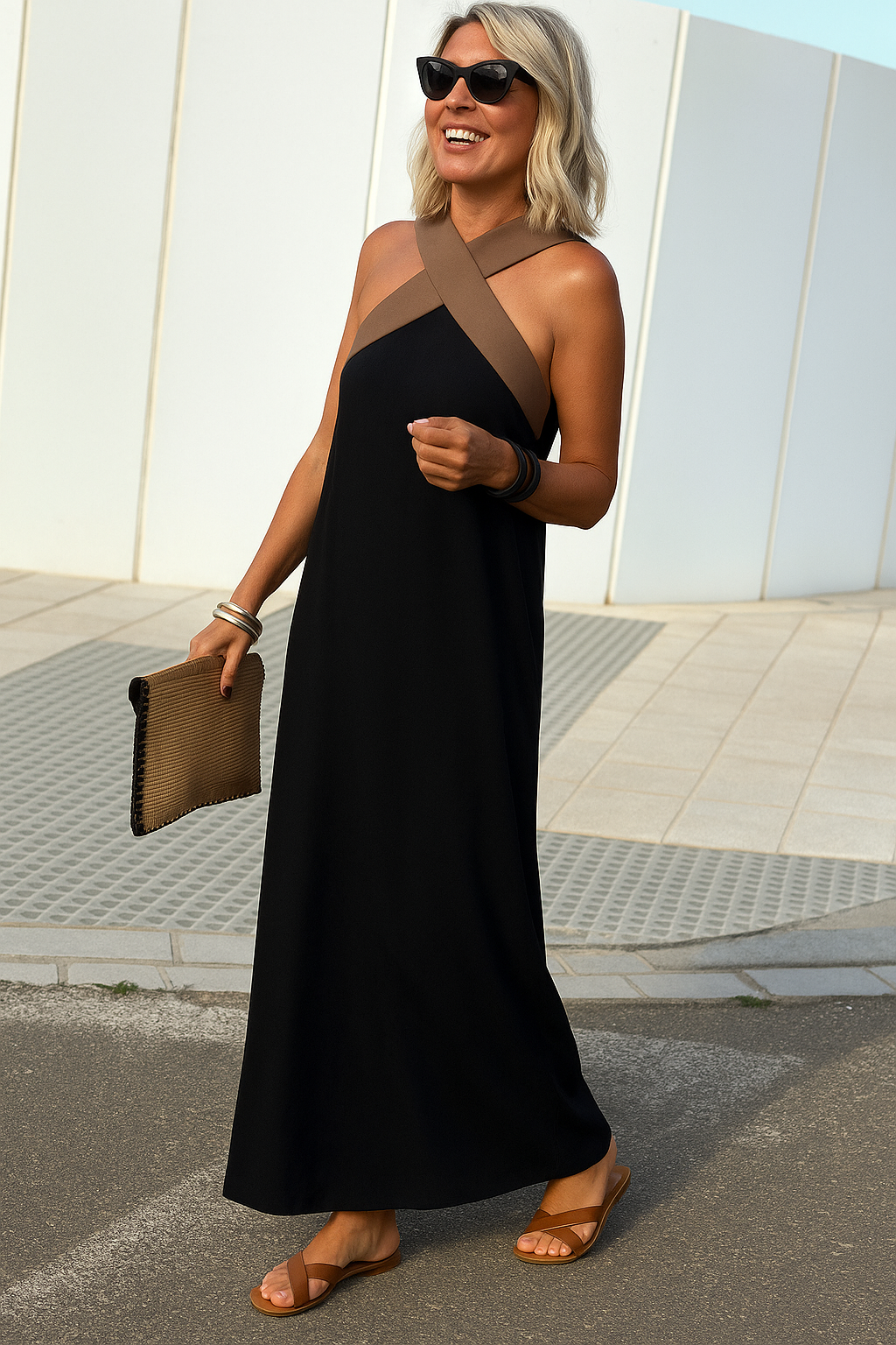 Woman in a black dress with brown accents standing outdoors.