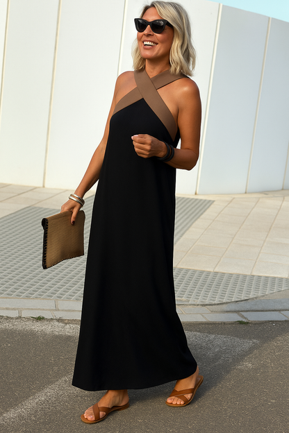 Woman in a black dress with brown accents standing outdoors.