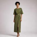 Woman wearing a green dress with a belt on a plain background