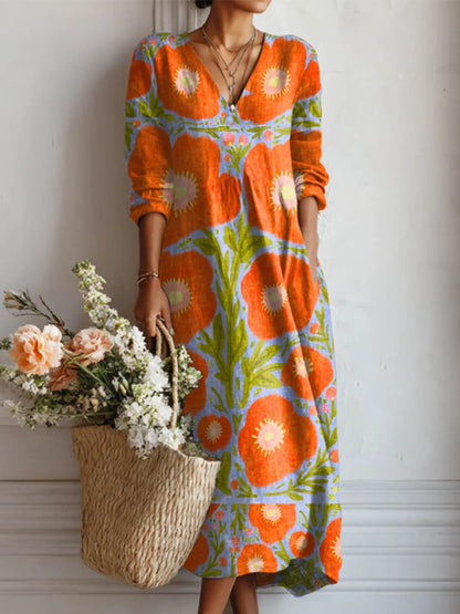 Woman wearing a colorful floral dress holding a woven bag with flowers against a white wall.