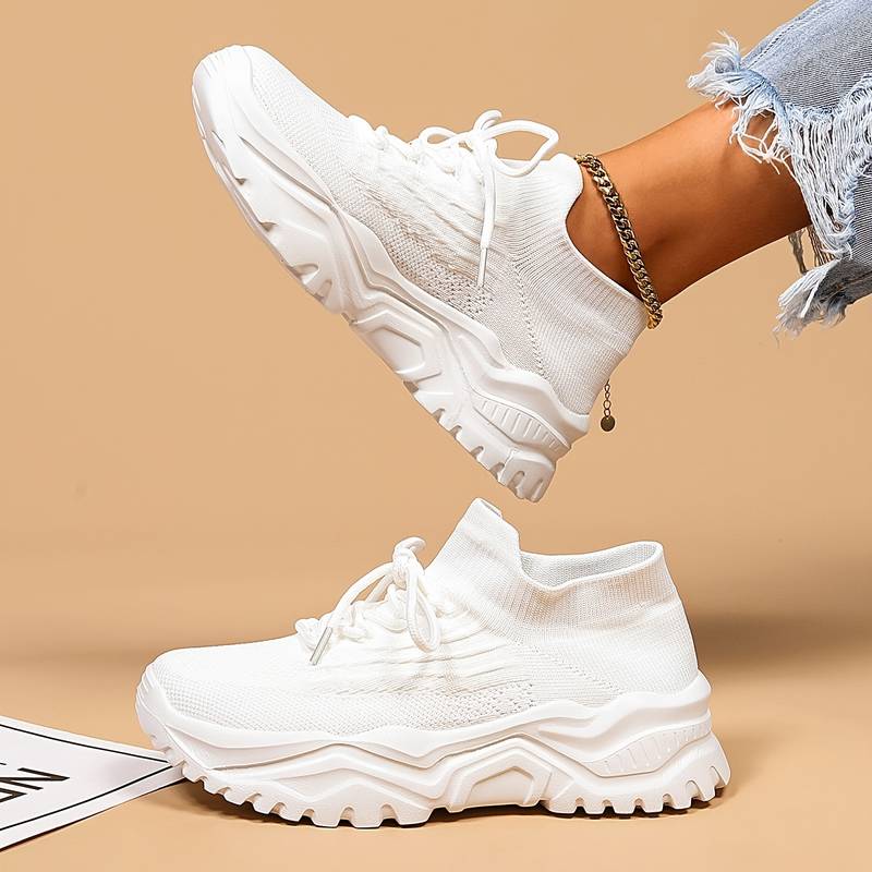 White sneakers worn with a beige background