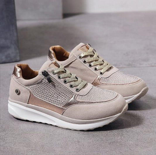 Pair of beige sneakers with white soles on a gray surface
