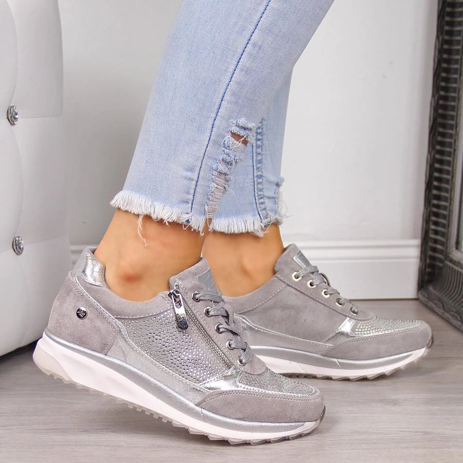 Gray sneakers worn with light blue jeans on a neutral background