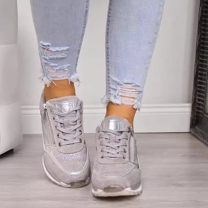 Silver glitter sneakers worn with ripped jeans on a neutral background