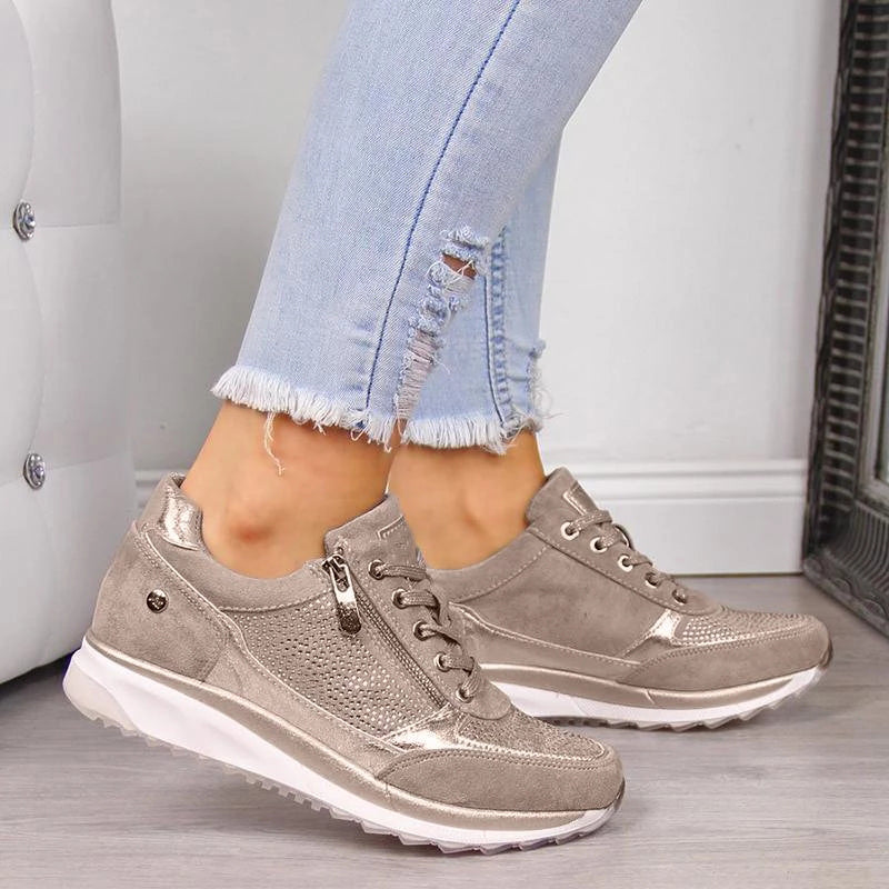 Beige sneakers worn with light blue jeans on a neutral background