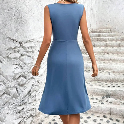 Woman wearing a blue dress standing on stone steps with a textured wall background