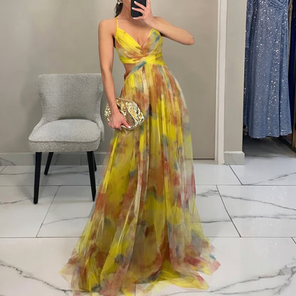Woman wearing a colorful dress in a room with a chair and another dress in the background.