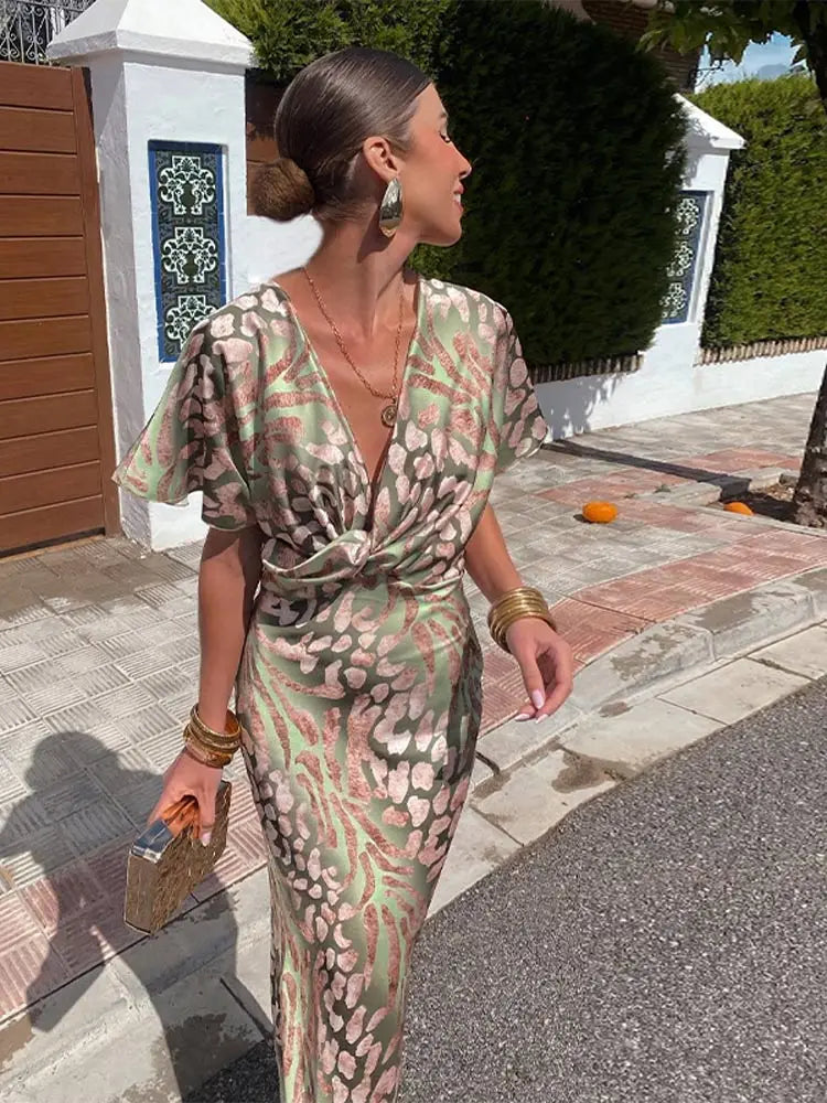 Woman in a patterned dress walking outdoors on a sunny day.
