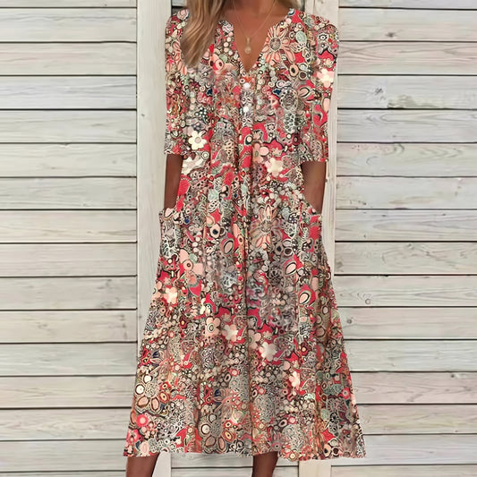 Woman wearing a floral dress standing against a wooden wall.