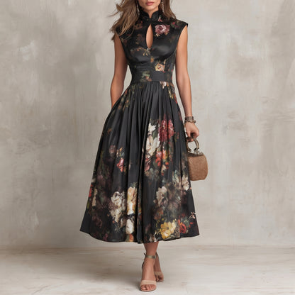 Woman wearing a black floral dress holding a small handbag against a neutral background
