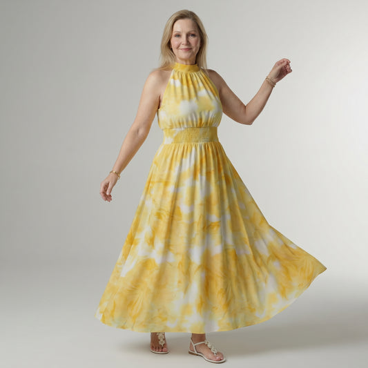 Woman wearing a yellow tie-dye dress against a plain background