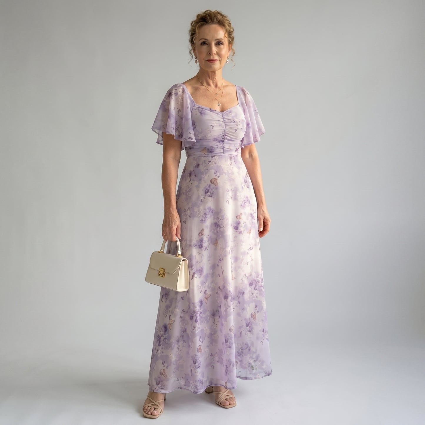 Woman wearing a purple floral dress holding a beige handbag against a plain background