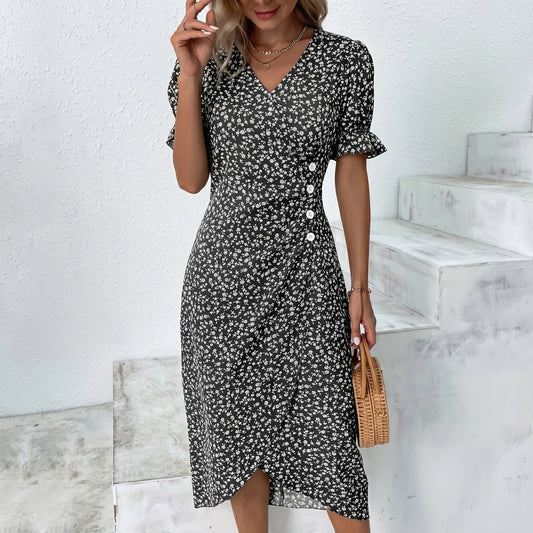 Woman wearing a black floral dress standing on a white staircase.
