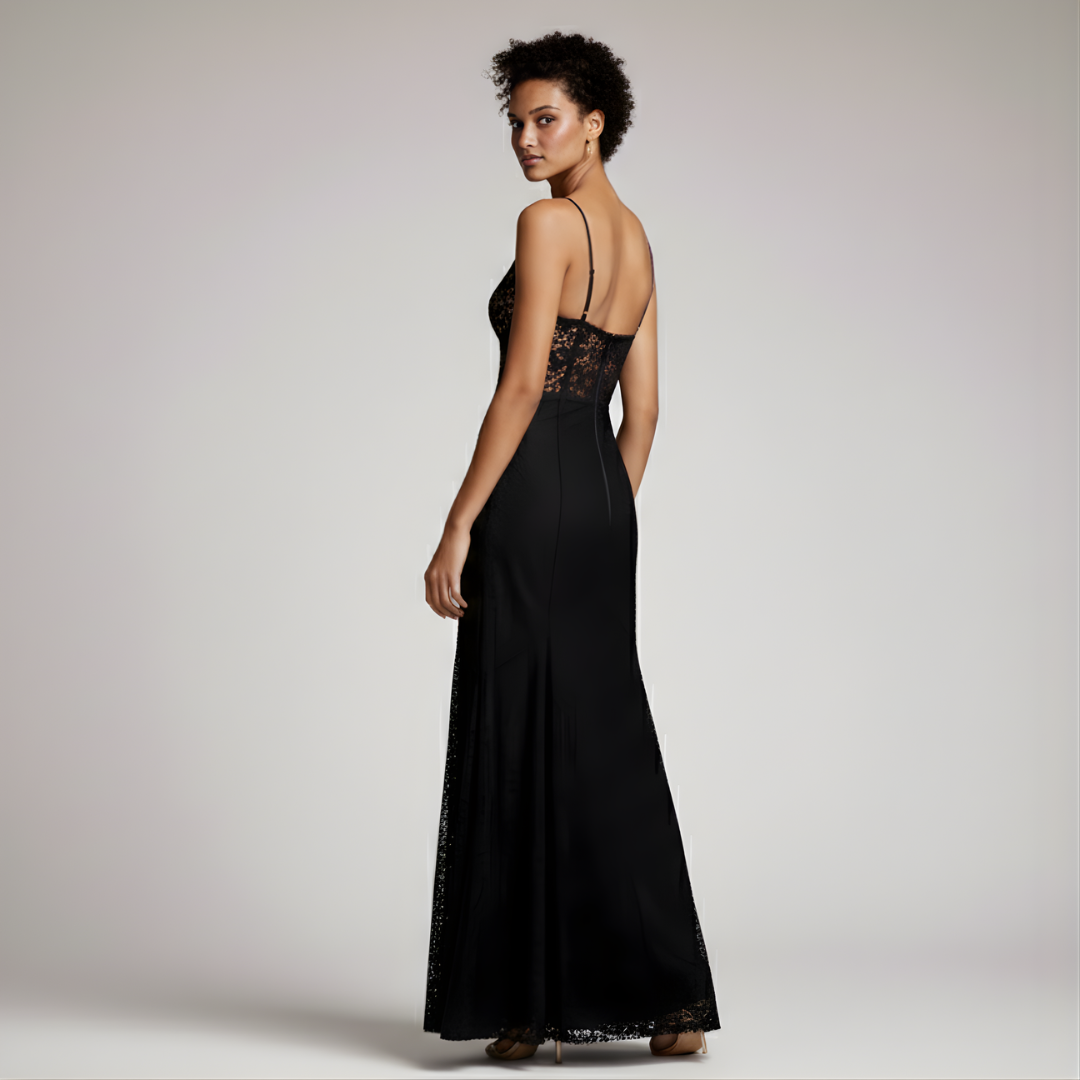 Woman wearing a black evening gown with lace detailing on a plain background