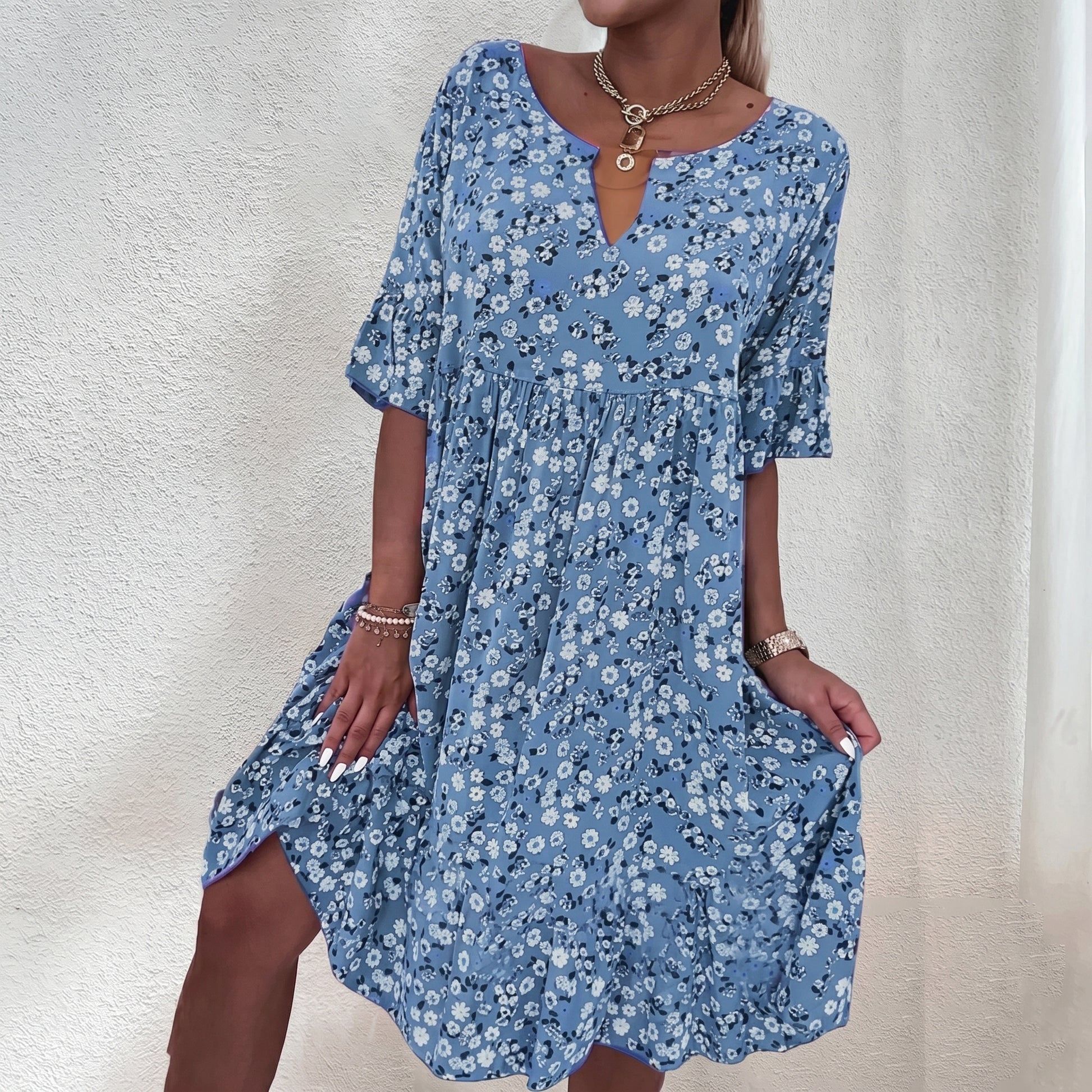 Woman wearing a blue floral dress against a neutral background