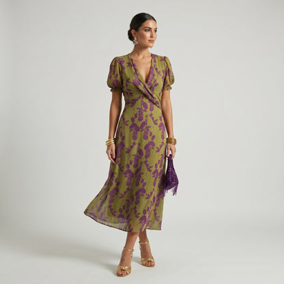 Woman wearing a green and purple floral dress on a white background