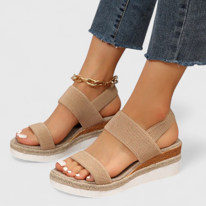 Beige sandals worn with blue jeans on a light gray background