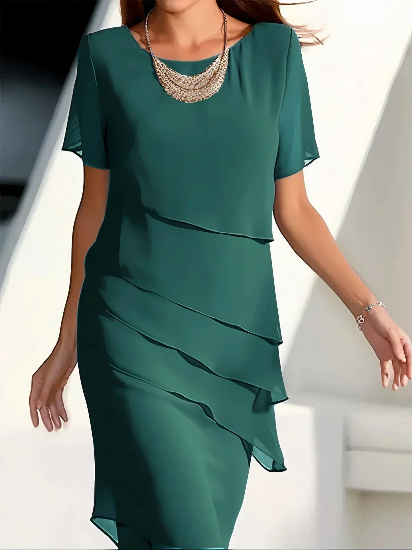 Green dress with ruffled layers worn by a person, against a neutral background
