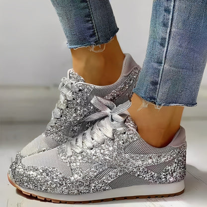 Silver glittery sneakers worn with blue jeans on a light background