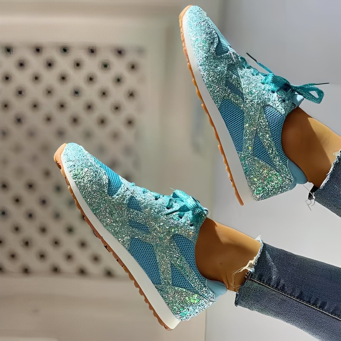 Blue glittery sneakers worn with jeans on a neutral background
