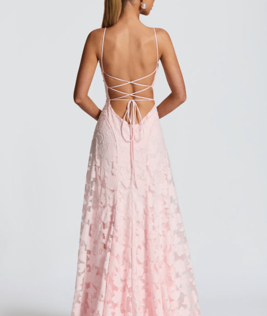 Pink lace dress with thin straps and open back on a plain background