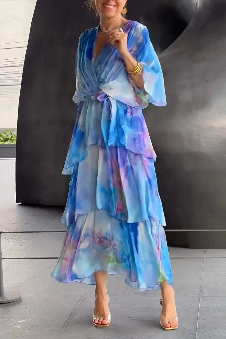 Woman wearing a colorful dress standing outdoors with a large sculpture in the background.