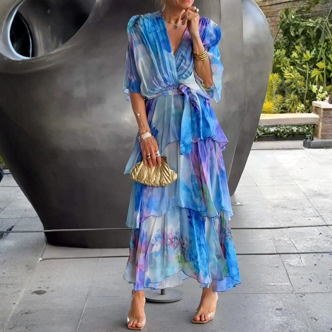 Woman wearing a colorful dress with a gold handbag in an outdoor setting