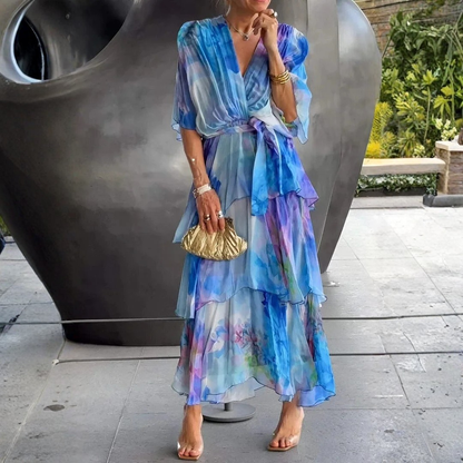 Woman wearing a colorful dress with a gold handbag in an outdoor setting