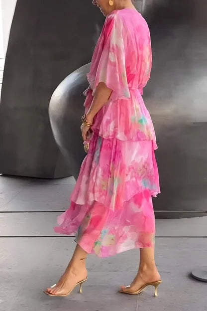 Person wearing a pink floral dress standing on a wooden floor with a dark background.