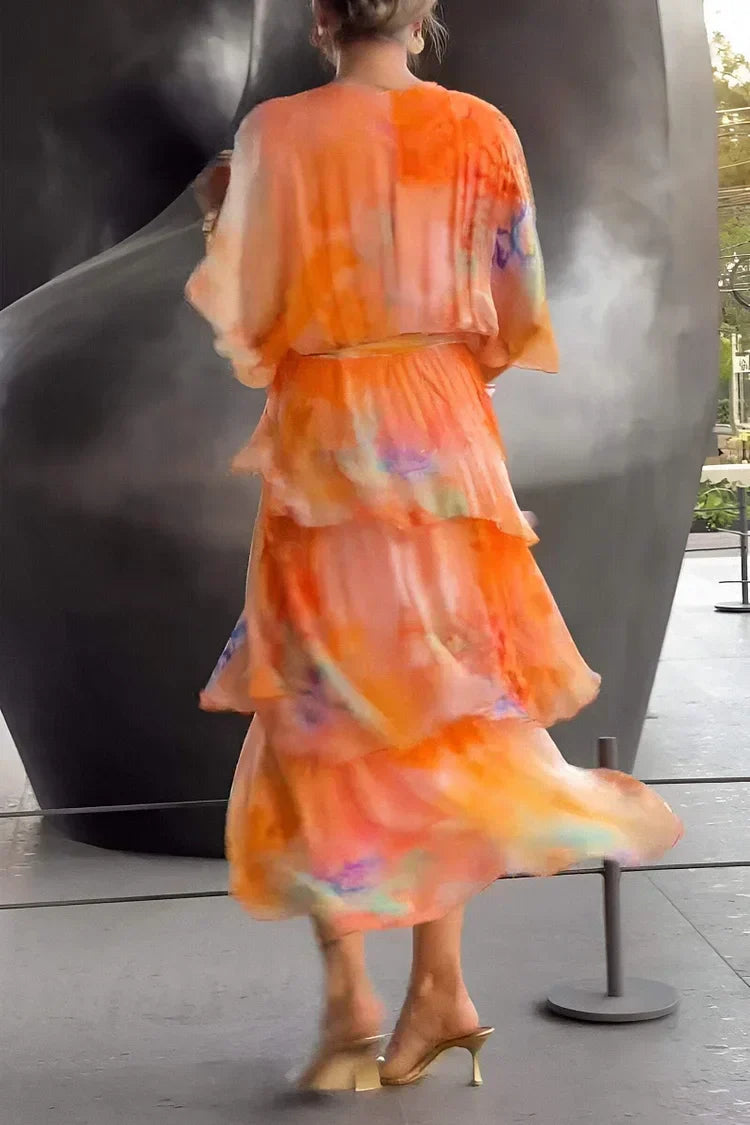 Person wearing an orange floral dress standing in front of a large black sculpture.