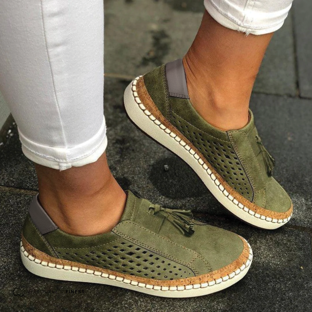 Green suede shoes with brown accents worn on a dark surface
