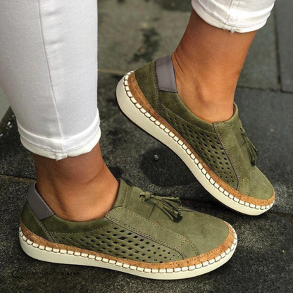 Green suede shoes with brown accents worn on a dark surface