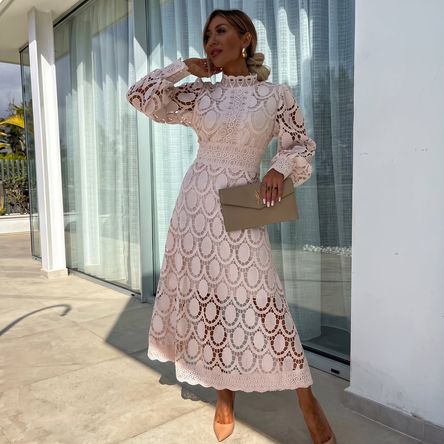 Woman in a white lace dress standing outside a modern building.