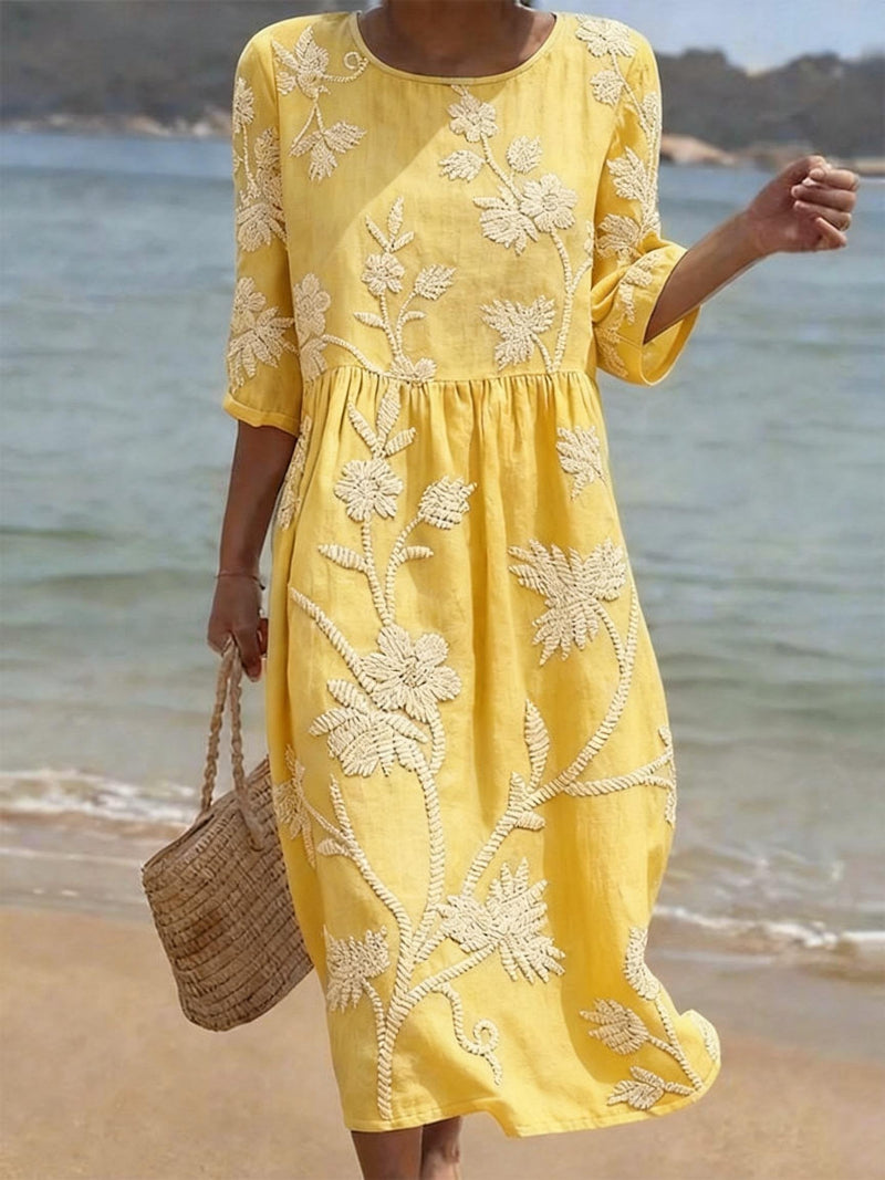 Woman wearing a yellow embroidered dress on a beach