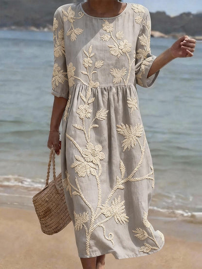 Woman wearing a gray dress with floral embroidery by the beach