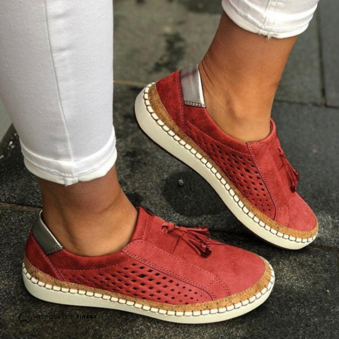 Red sneakers with white soles worn on a pavement