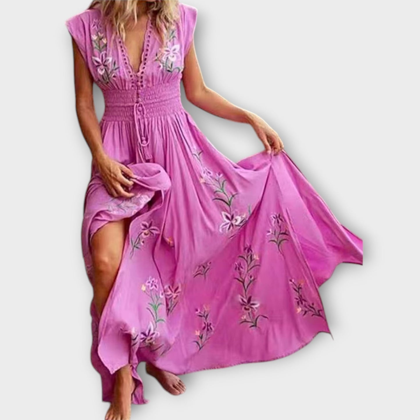 Pink dress with floral embroidery being held by a person on a white background