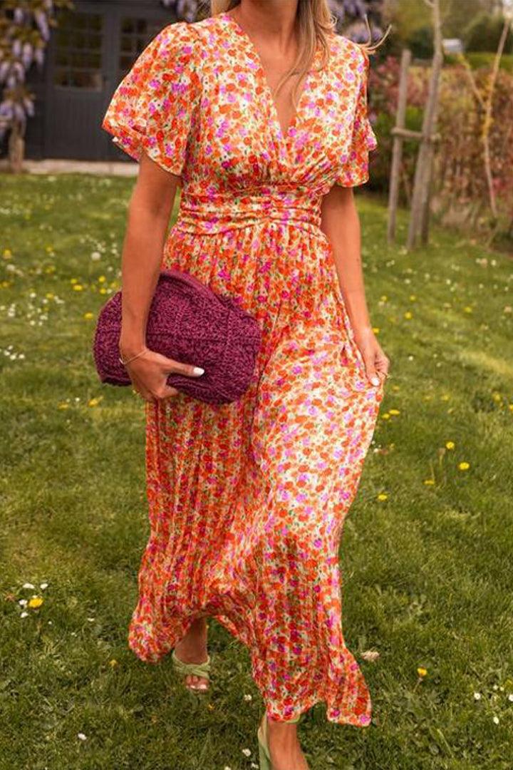 Woman in a colorful floral dress holding a matching clutch in a garden setting