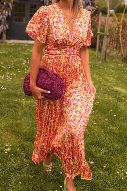 Woman in a colorful floral dress holding a matching clutch in a garden setting