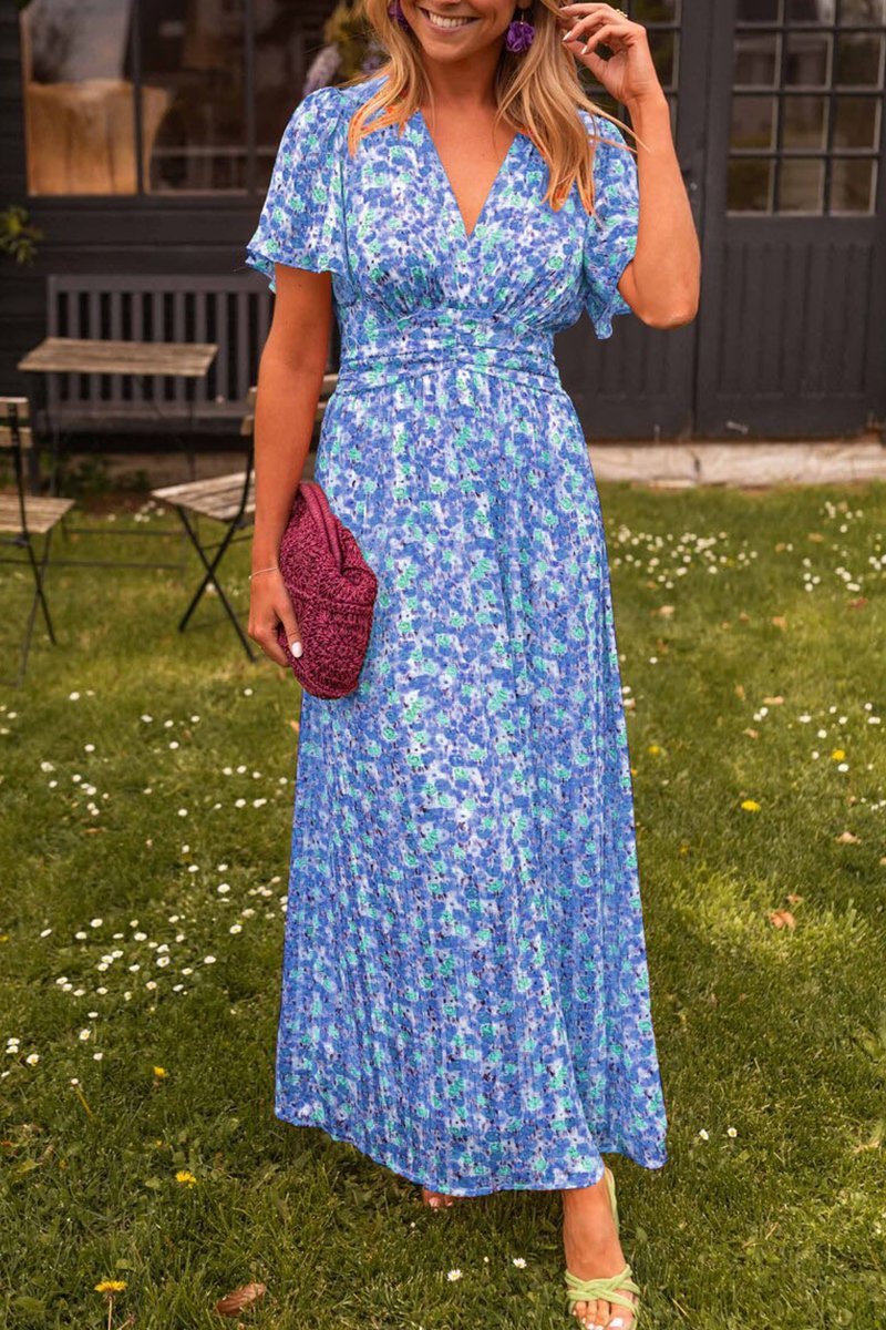 Woman in a blue floral dress standing outdoors on grass