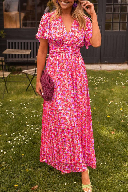 Woman in a pink floral dress standing outdoors on grass