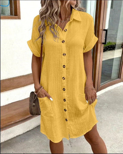 Woman wearing a yellow dress with buttons, standing outdoors.