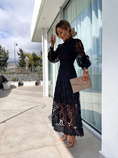 Woman in a black lace dress standing outside a modern building.
