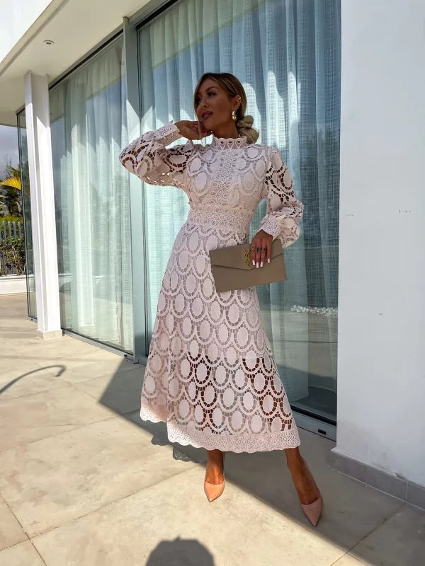 Woman in a white lace dress standing in front of a modern building.