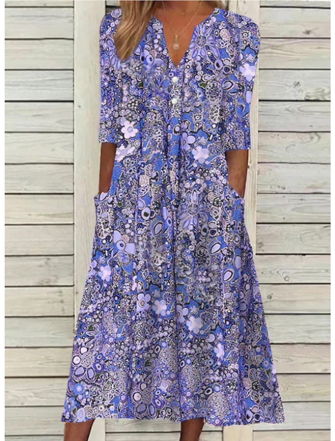 Woman wearing a blue floral dress against a wooden background