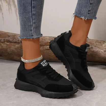 Black sneakers worn with light blue jeans on a neutral background