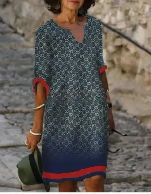 Woman wearing a blue patterned dress with red accents on a stone path.